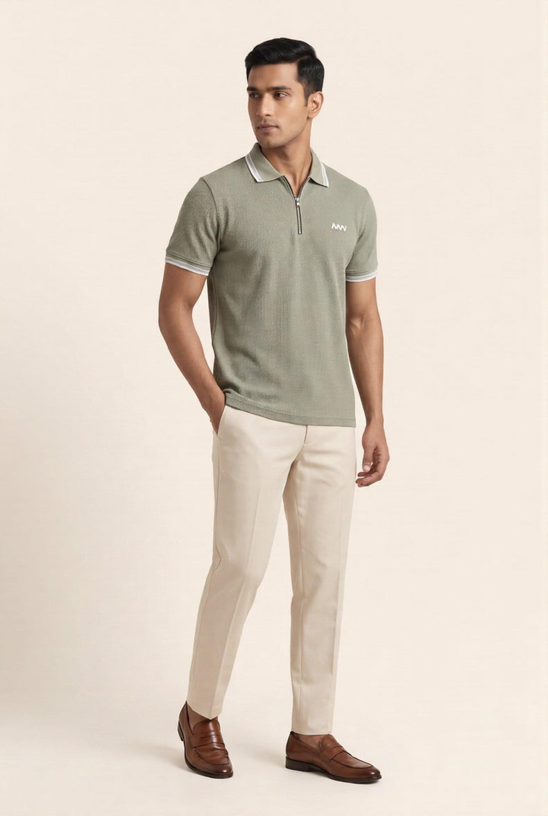Man wearing olive green textured polo shirt with white trim, beige chinos, and brown loafers — modern men's fashion