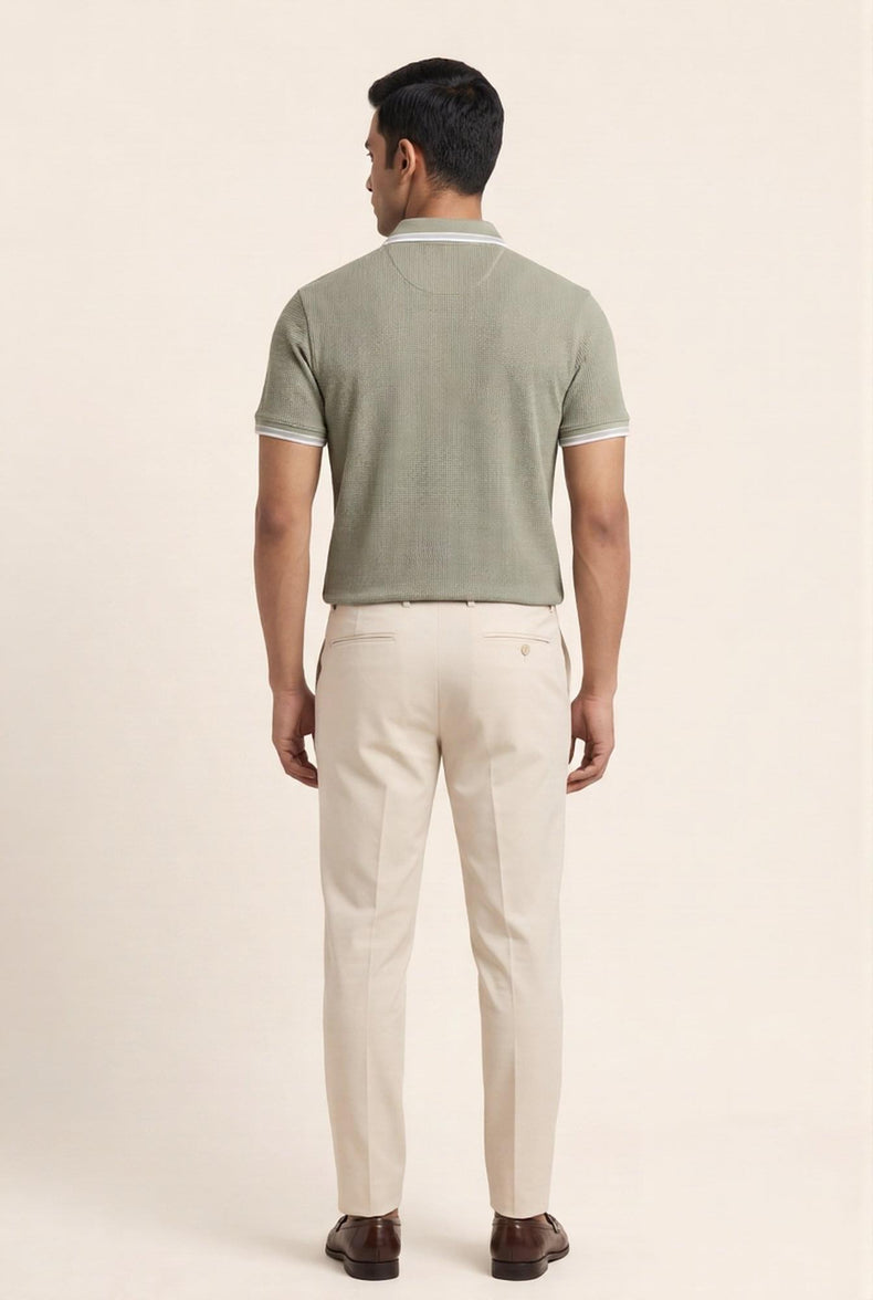 Man in olive green textured polo shirt with white trim, paired with beige chinos and brown loafers — modern men's fashion
