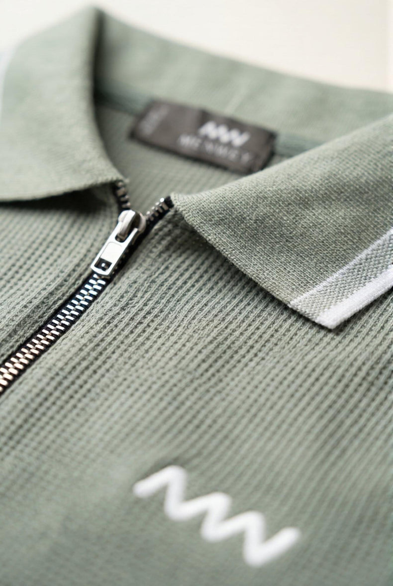 Olive green men's ribbed polo shirt with white trim and zipper, premium fabric detail
