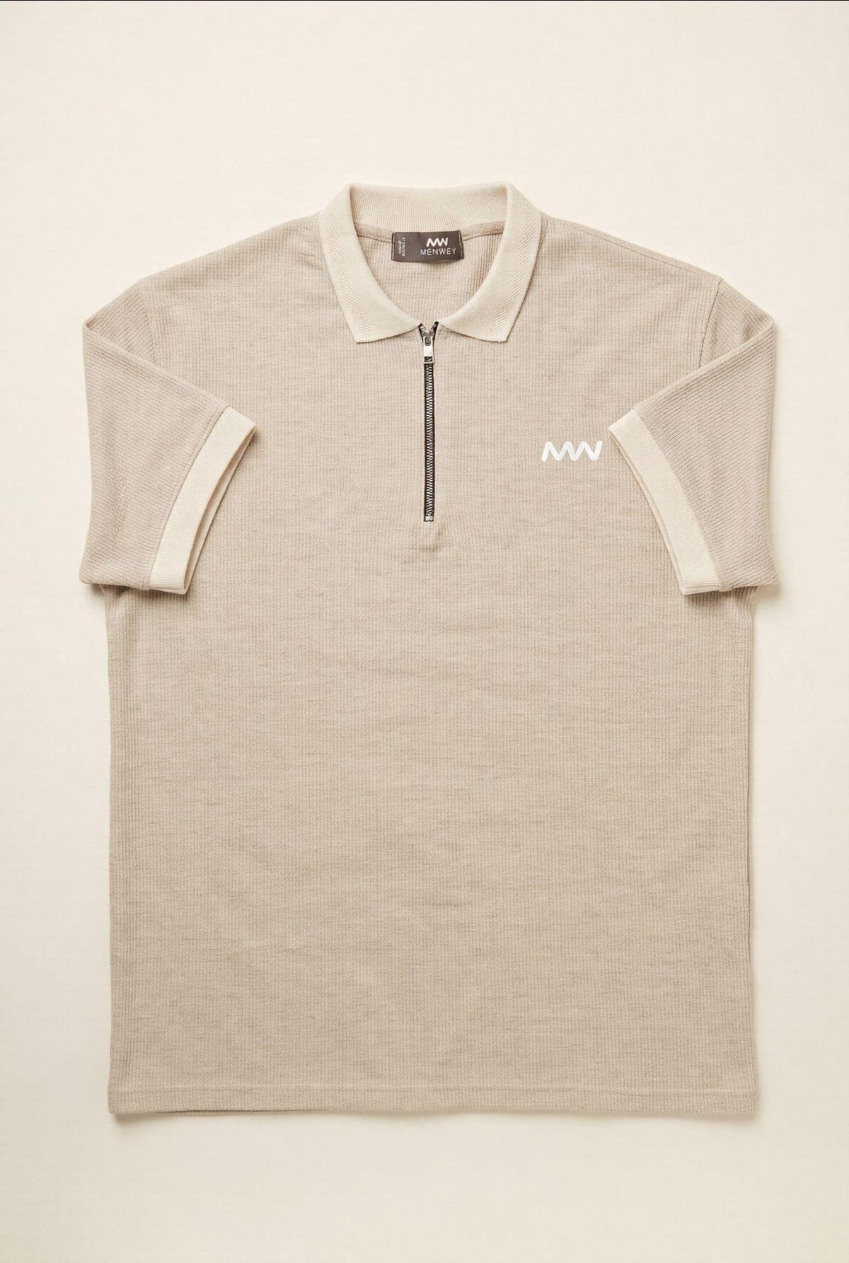Beige men's polo shirt with half-zip, ribbed texture, and white logo — premium menswear style