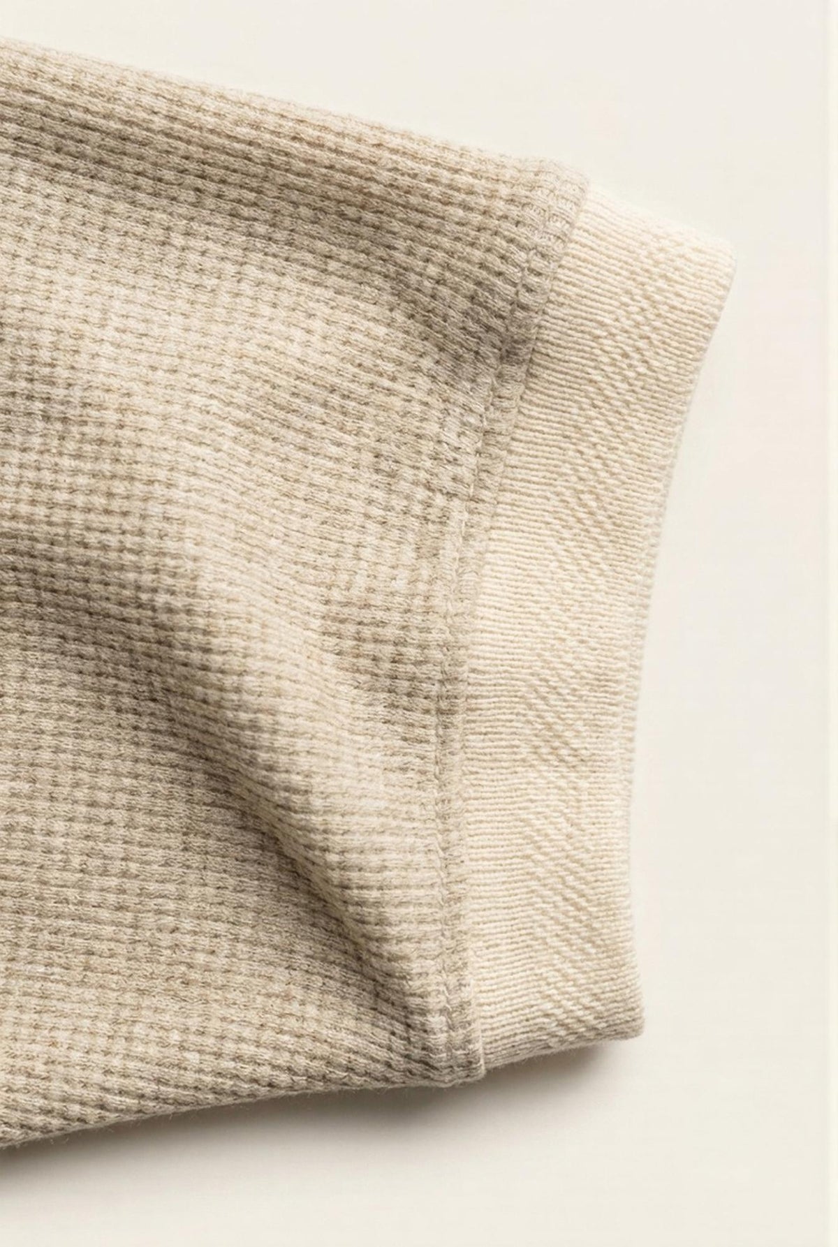 Beige men's sweater sleeve with ribbed knit texture and clean stitching detail