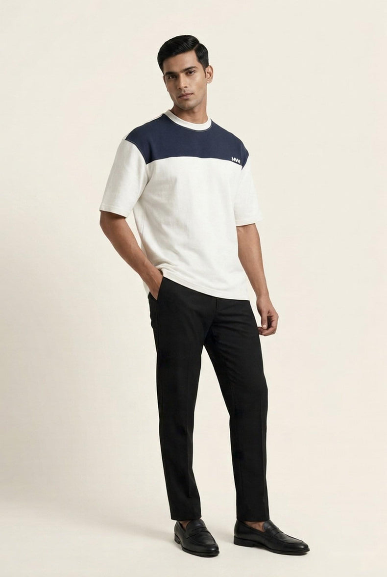 Man wearing white and navy color-block t-shirt with black trousers and loafers — modern men's fashion