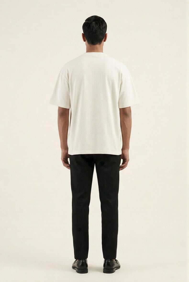 Man wearing premium off-white t-shirt and black trousers, back view — modern men's fashion essentials